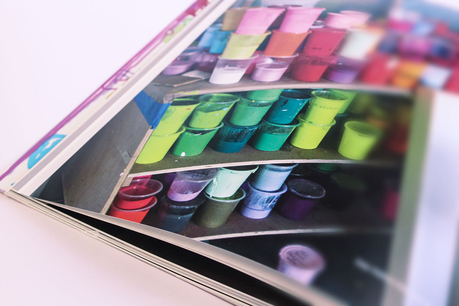 Aufgeschlagener Katalog der Galerie Thomas mit einem Foto von Regalen voller bunter Farbbecher